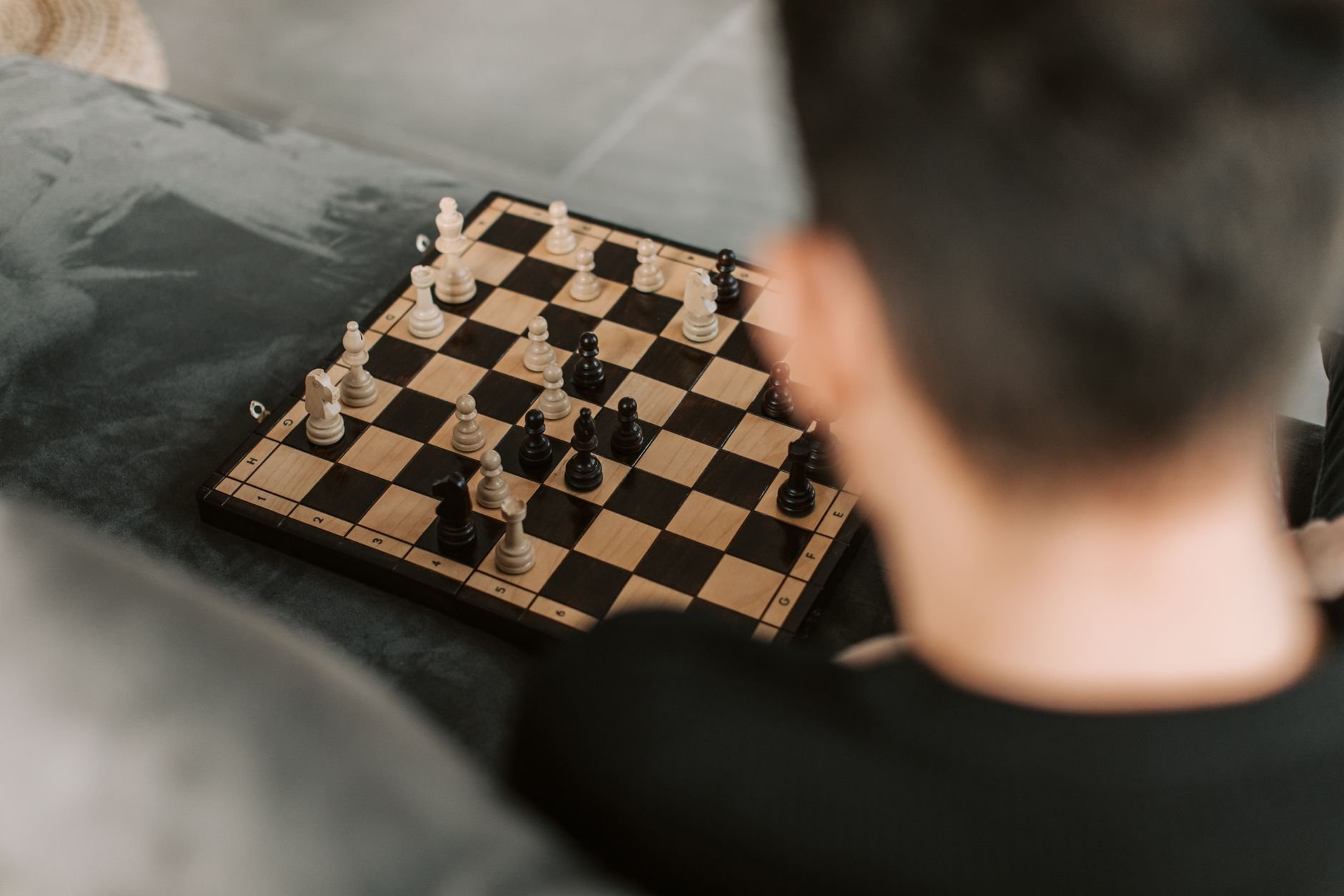 A person intensely focusing on a chess game. Close-up, board view, strategic play.